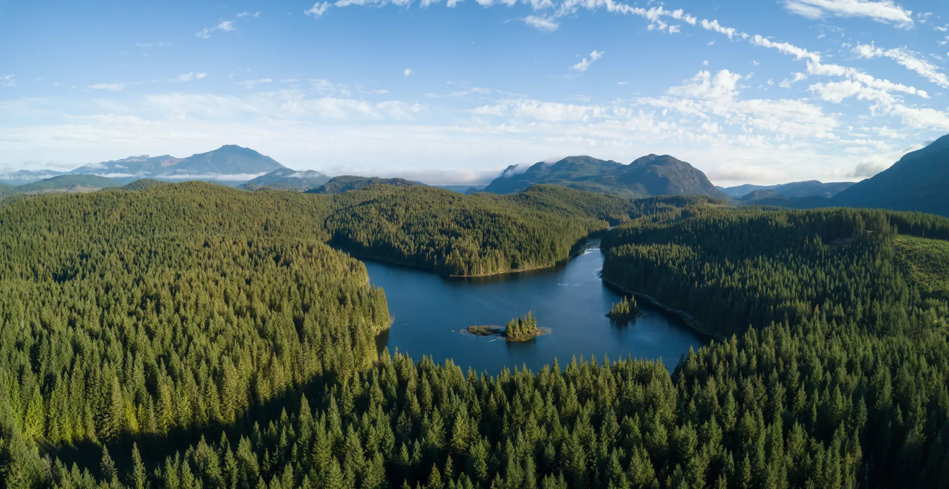 Aerial view of a Canadian landscape of dense forest wrapped around a wide blue lake.