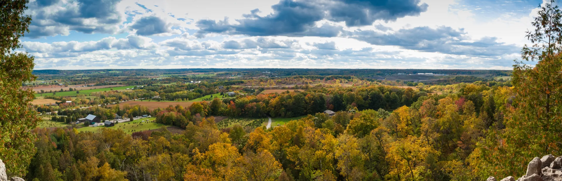 High-angle panorama of countryside, woodland and settlement spread across a valley.