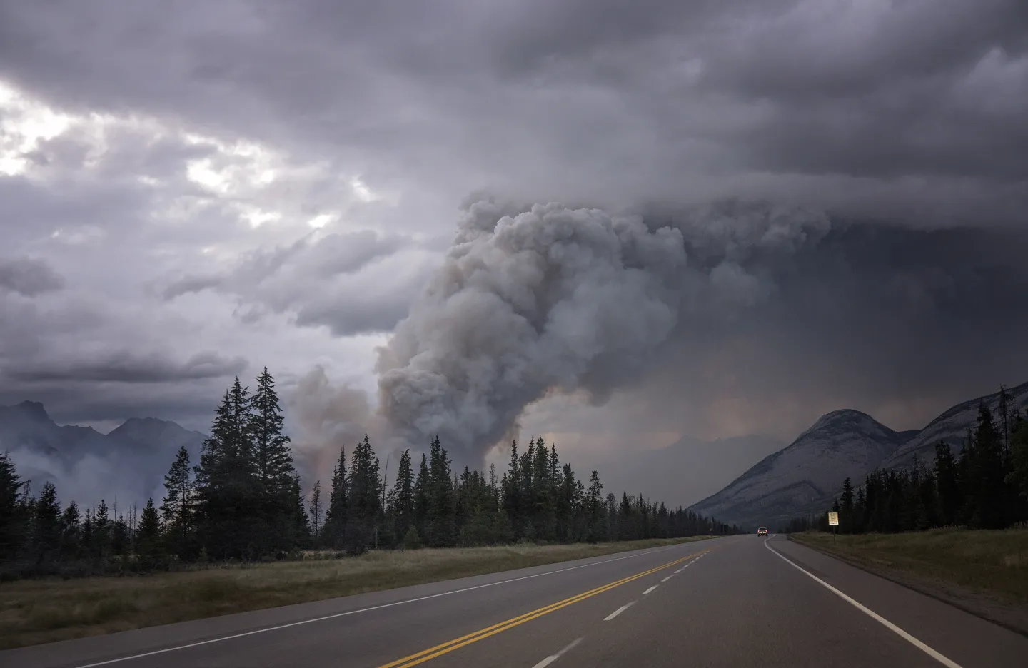 Plumes of wildfire smoke blowing across a highway, reducing visibility for traffic.